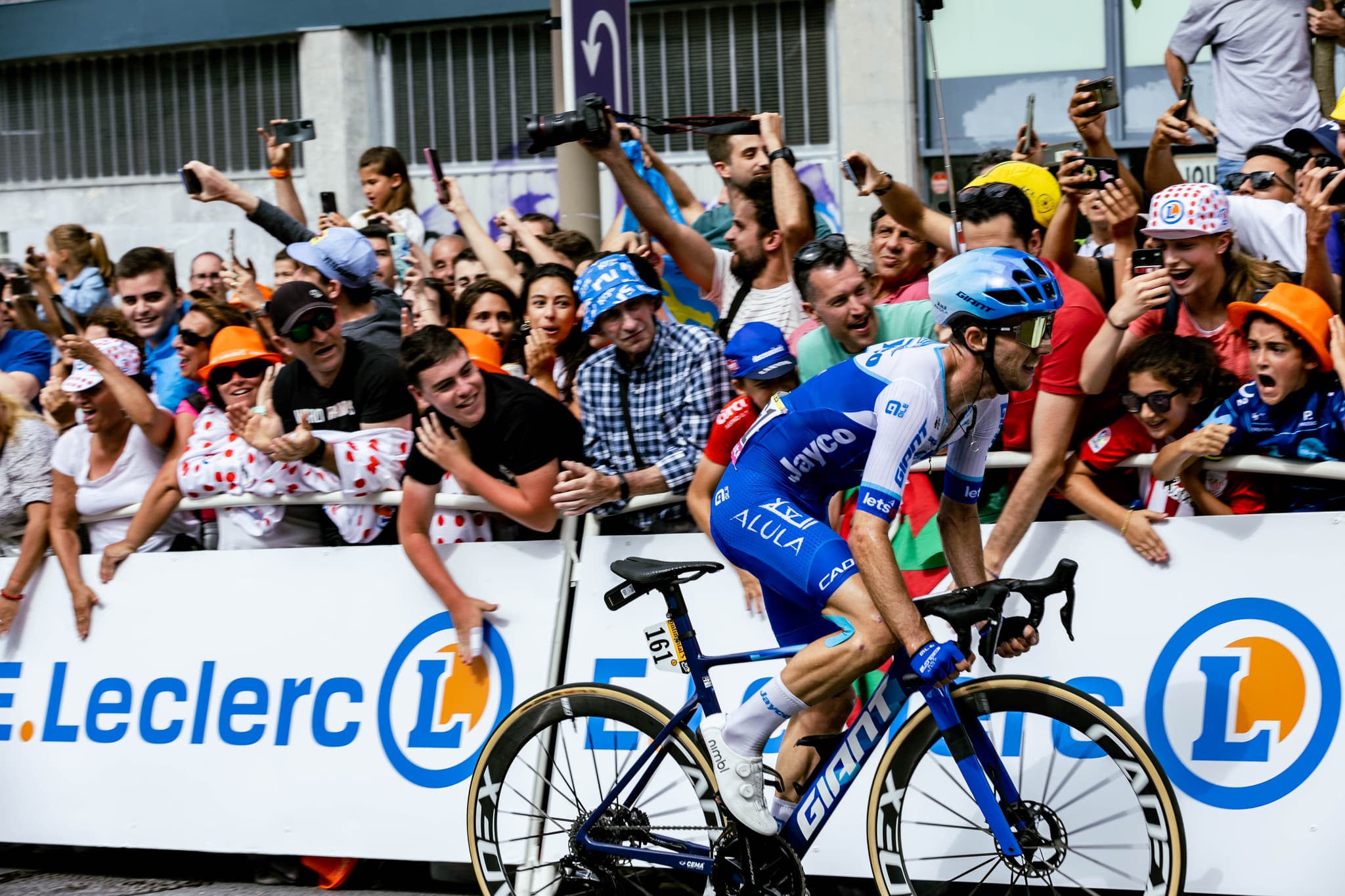 Cyclist in Jayco AlUla kit surrounded by fans at Tour de France